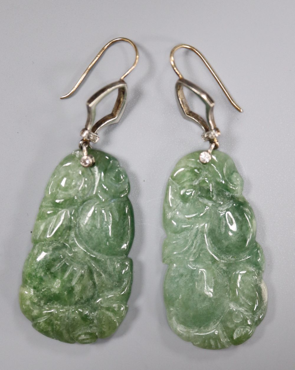 A pair of yellow and white metal mounted carved jade and diamond chip set earrings, jade 35mm, gross 14.6 grams.